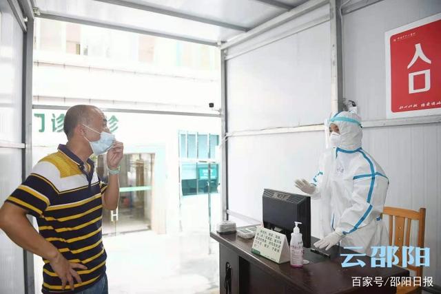 邵阳市中心医院预检分诊点，穿着隔离服的工作人员与前来咨询的市民
