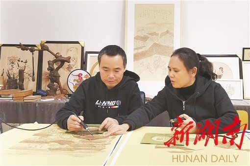 唐文林和王艳萍在绘制烙画。 