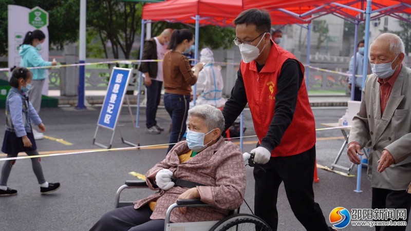 在邵阳市第五中学，志愿者帮助行动不便的老人完成核酸检测
